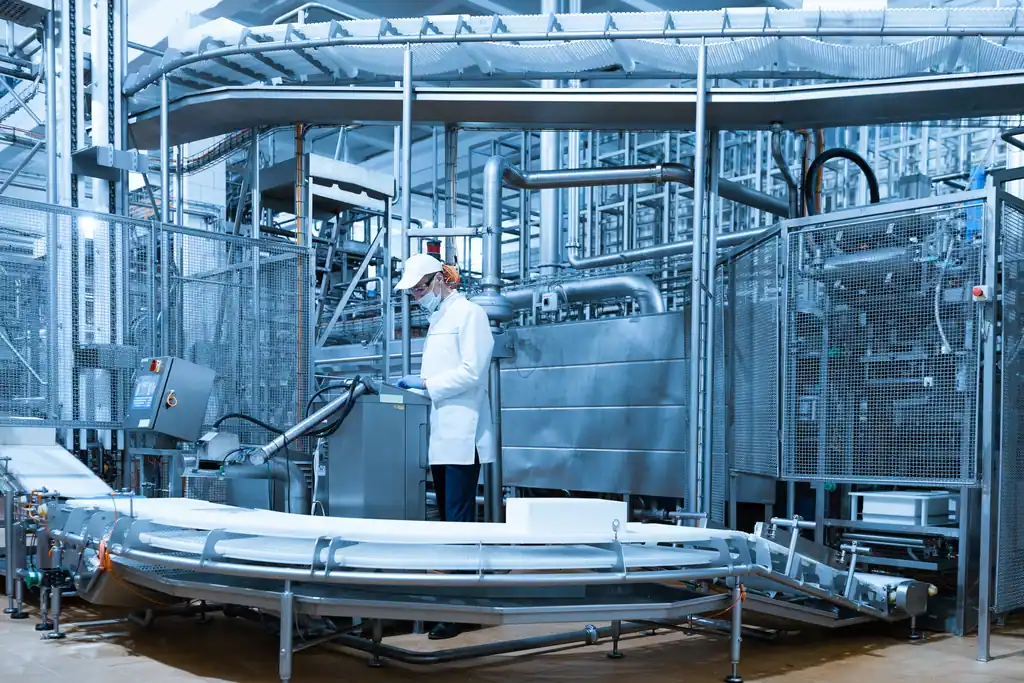 Linha de produção de laticínios com esteira em inox e técnico ajustando o painel