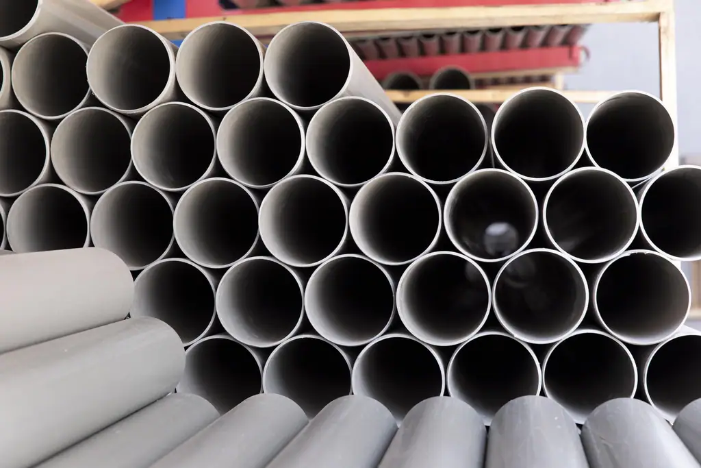 Tubos plásticos rígidos de PVC extrudados empilhados em galpão industrial